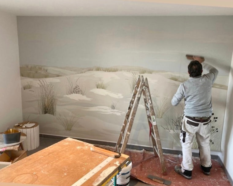 Pose d'un papier peint panoramique sur un mur, depuis un escabeau